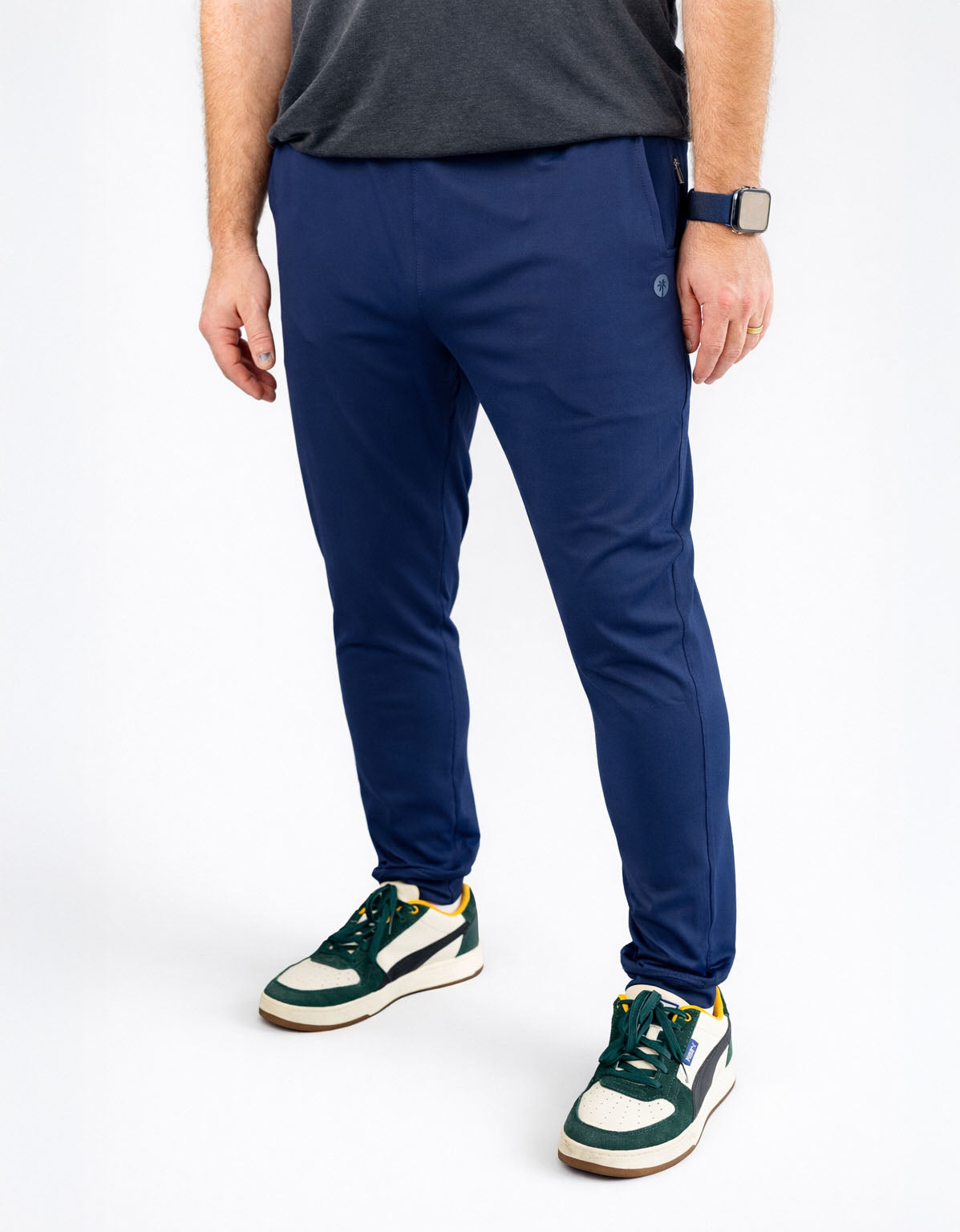 Person wearing blue pants and green sneakers on a white background