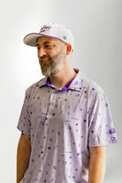 Man wearing a patterned shirt and cap against a plain background