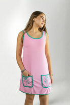 Woman wearing a pink dress with green trim on a white background