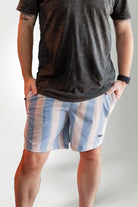 Person wearing a dark t-shirt and striped shorts on a plain background