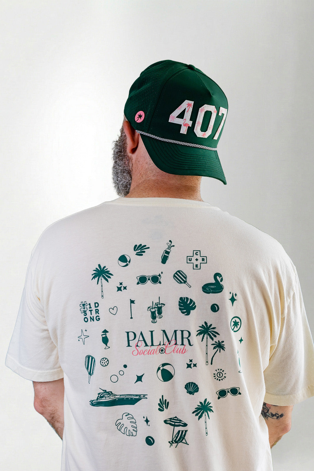 Person wearing a white t-shirt with green graphics and text, and a green cap with '407' on a light gray background.