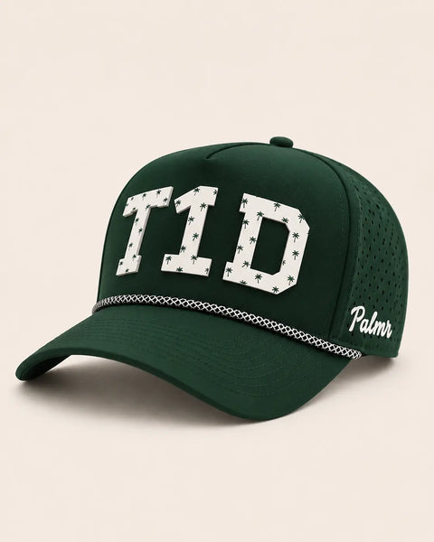 The T1D Signature Hat (Green): dark green rope snapback with T1D in white palm-print letters, perforated sides, Palmr script logo.