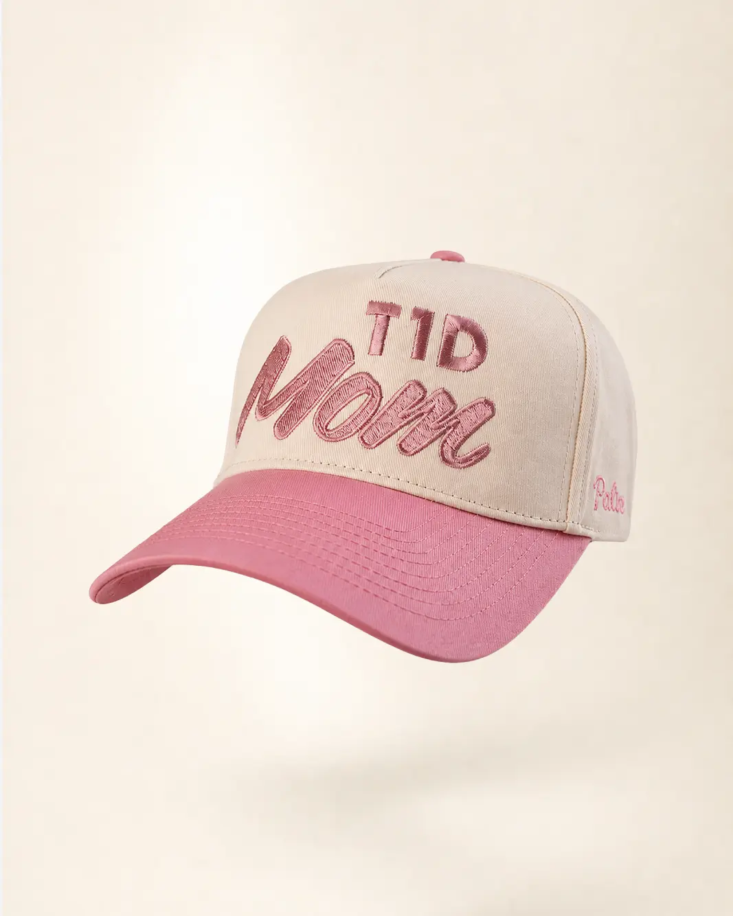 A baseball cap with a cream-colored crown and a dusty pink brim, featuring 'T1D Mom' embroidered in pink on the front. The brand name 'Pals' is visible on the side.