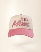 A baseball cap with a cream-colored crown and a pink brim, featuring the text 'TID Mom' embroidered in pink on the front.