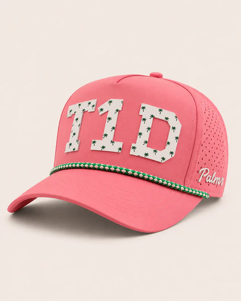 The T1D Signature Hat (Pink): pink rope snapback, white T1D letters with small green palm trees, green and white rope, perforated sides.