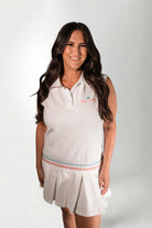Woman wearing a white sleeveless polo shirt and skirt with a logo on a white background