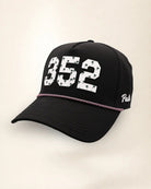The 352 Signature Hat (Black), three-quarter view: white raised 352 with small palm print on a black rope snapback, pink and white rope, white Palmr script.