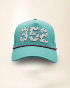 The 352 Signature Hat (Teal), front view: white raised 352 with small palm print on a teal crown, pink and black rope along the brim.