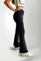 Person wearing black flared pants and a white crop top on a light gray background