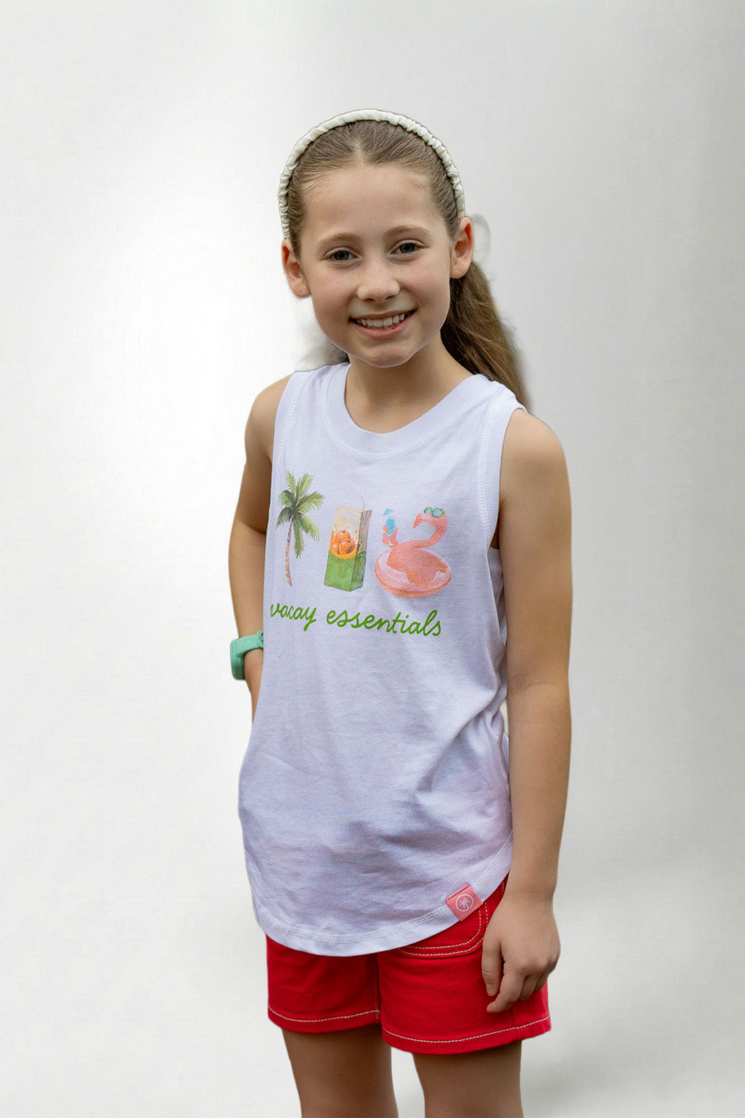 Young girl wearing a white sleeveless shirt with graphics and text, standing against a plain background
